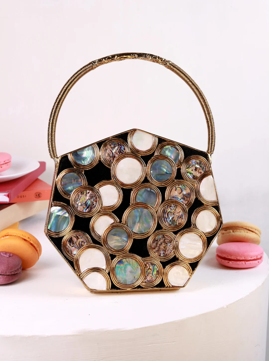 Hexagonal handbag with circular cutouts and gold accents on a white background