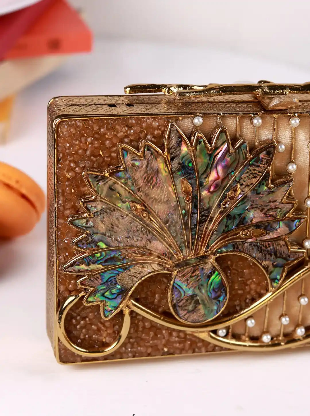 Decorative compact mirror with leaf design and pearl embellishments on a white background
