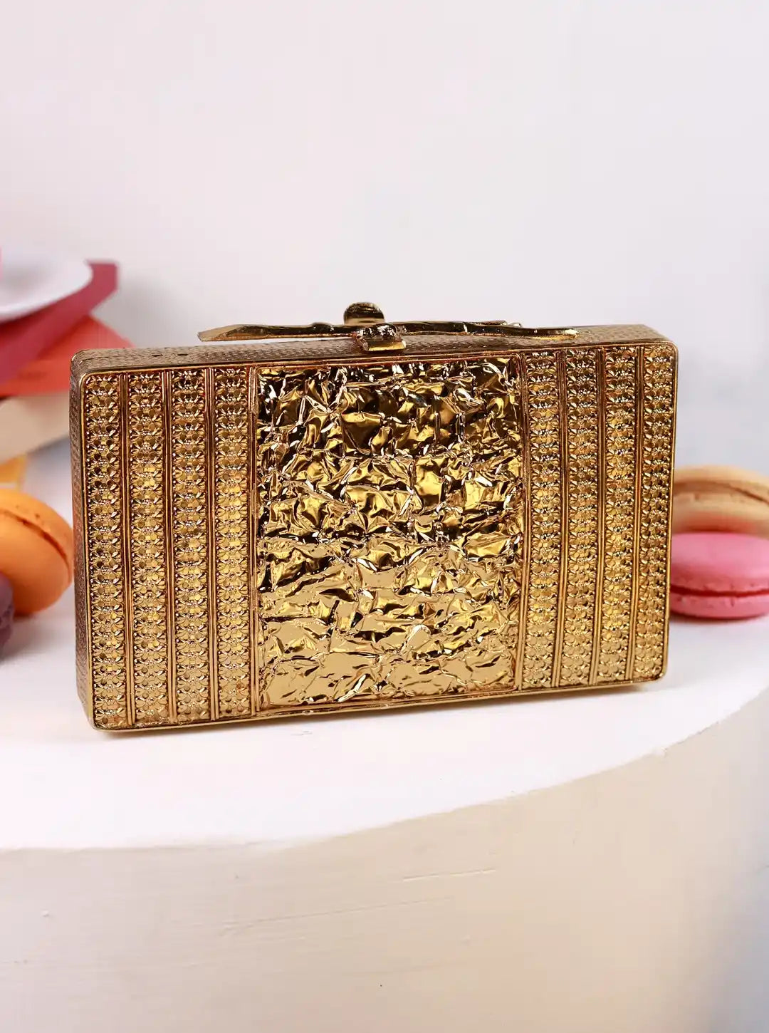 Gold clutch bag with intricate design on a white background