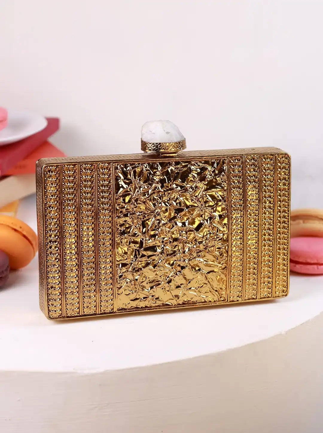 Gold clutch bag with intricate design on a white background