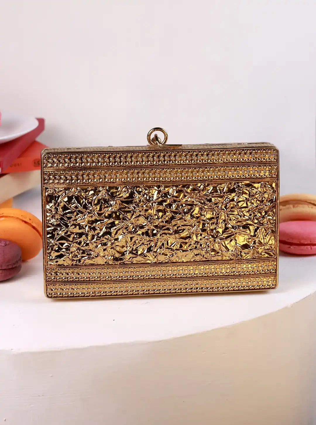 Gold clutch bag with intricate design on a white background