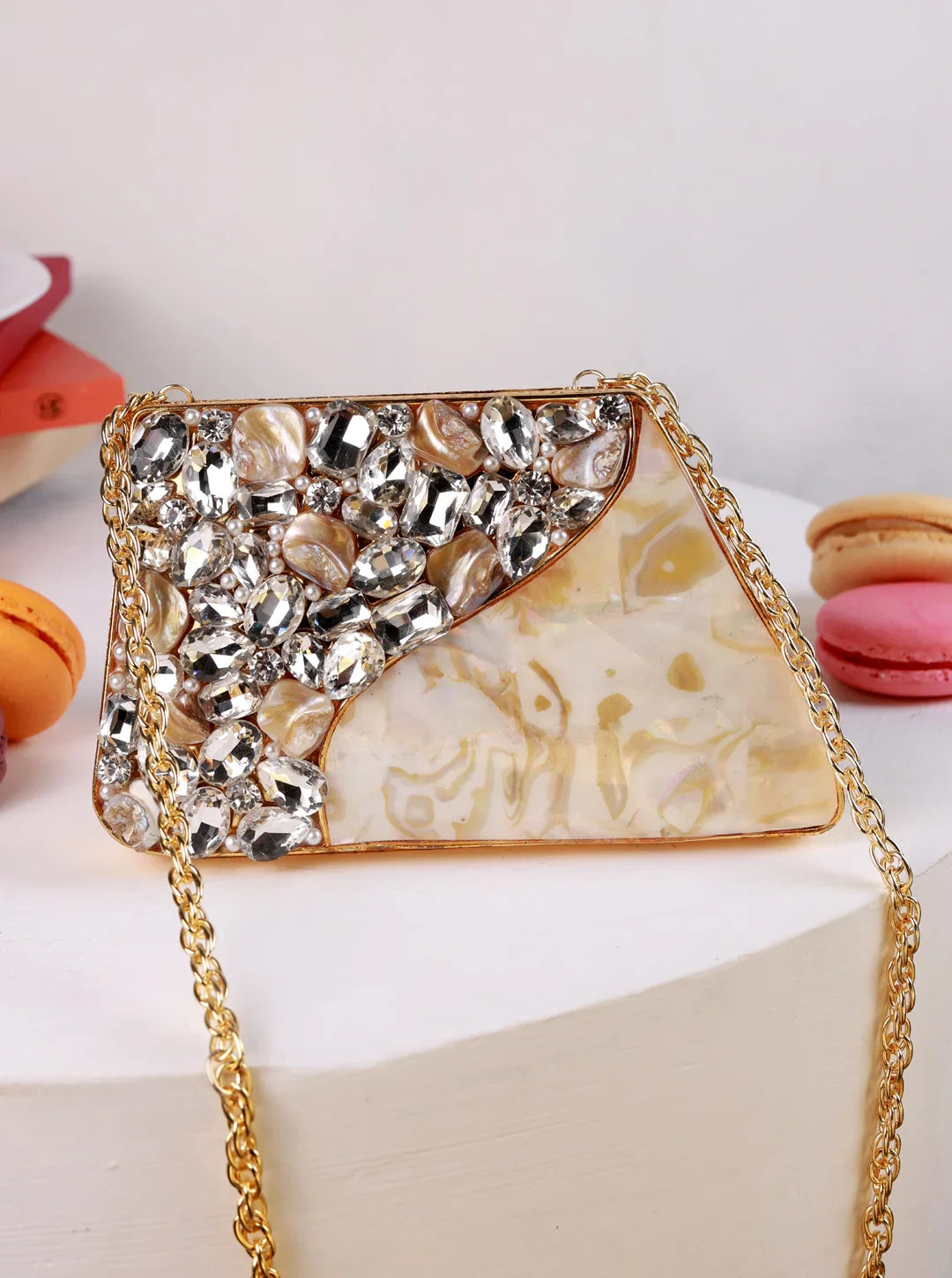 Decorative handbag with gemstones on a white surface with macarons in the background