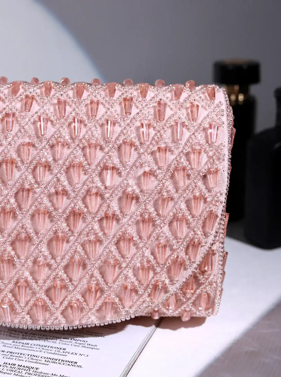 Pink beaded clutch on a surface with a blurred background