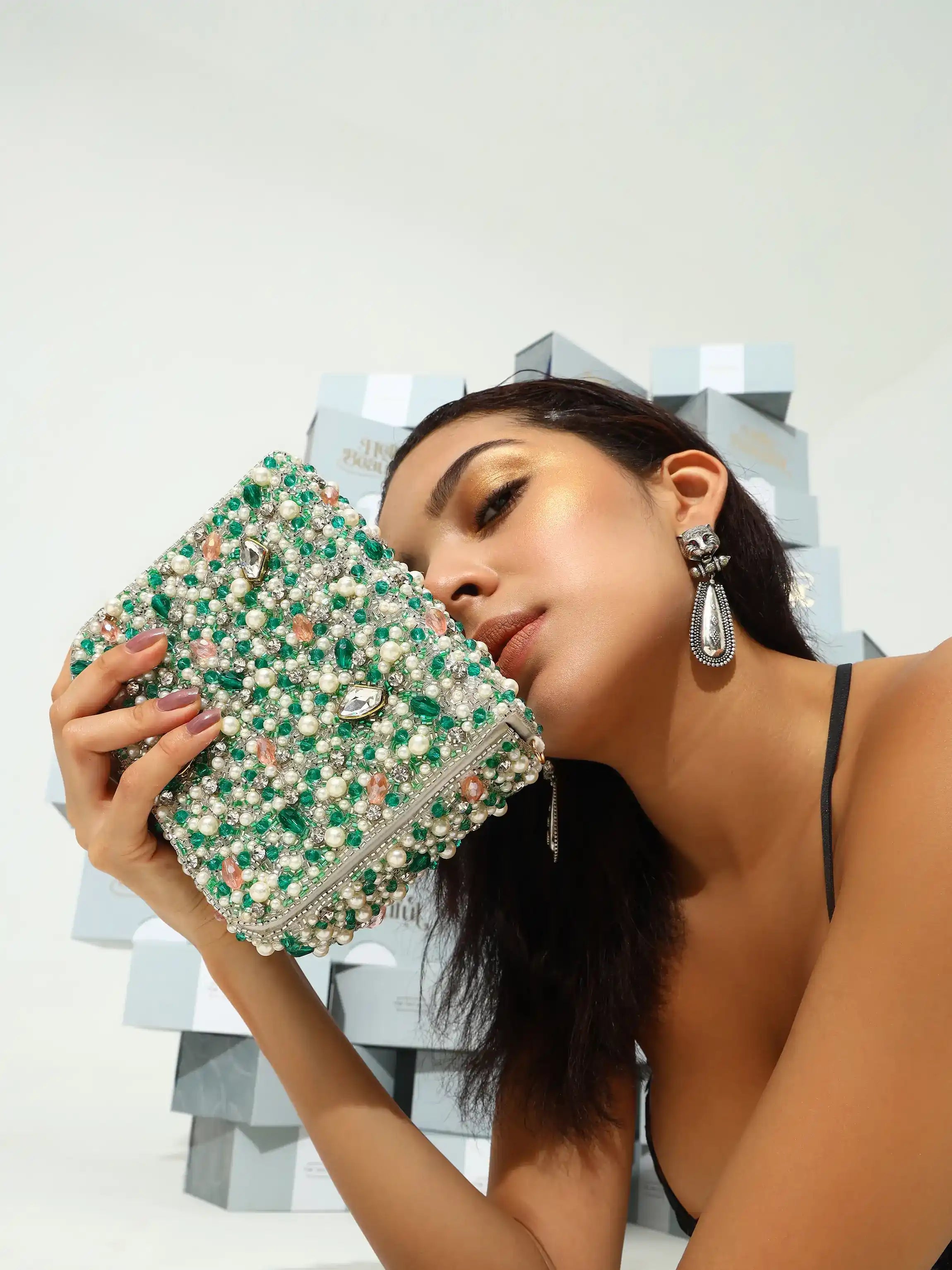 Woman holding a green beaded clutch with a geometric background