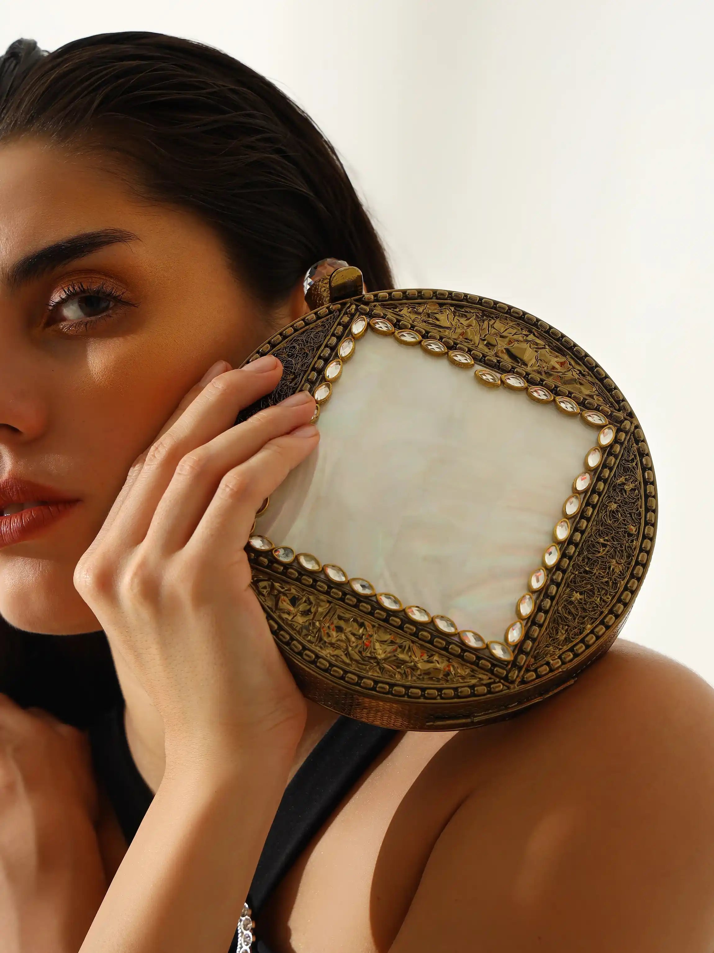 Woman holding a decorative clutch with intricate design