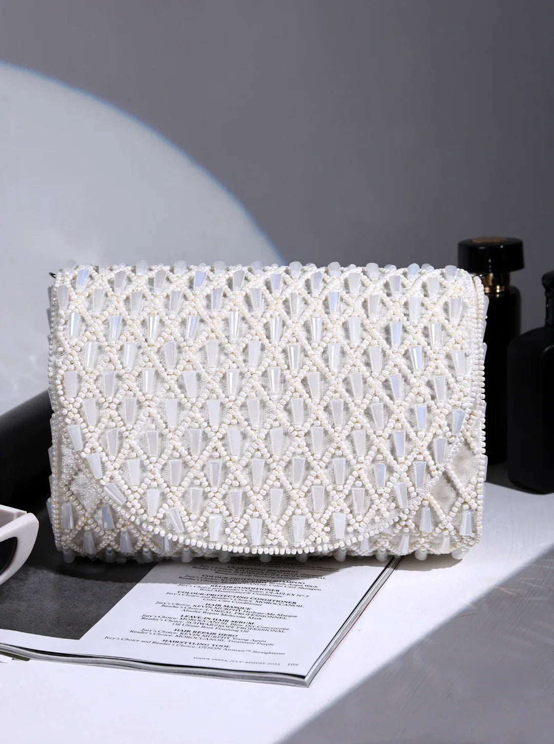 White beaded clutch bag on a magazine with a gray background