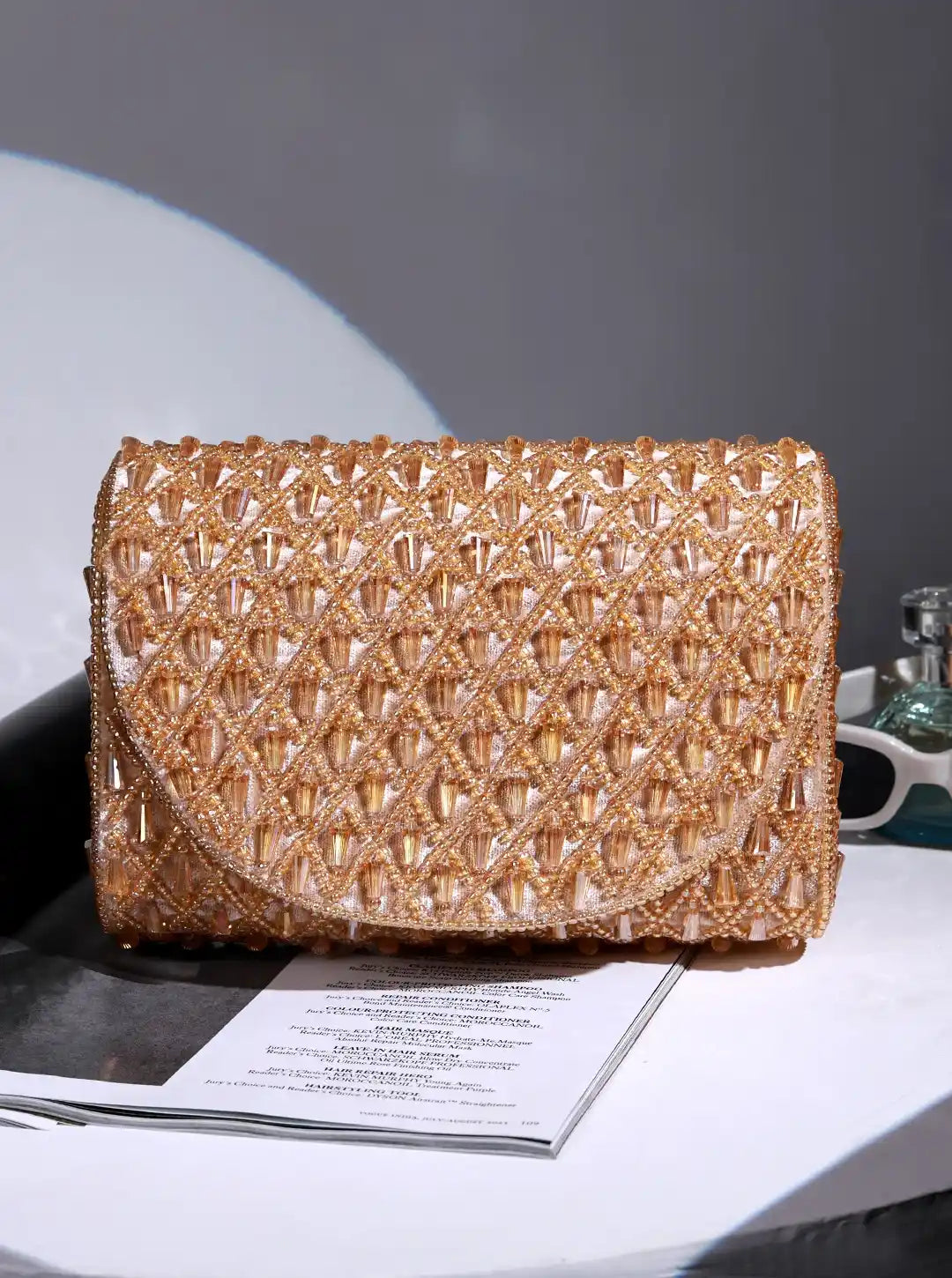 Gold beaded clutch bag on a magazine with a gray background