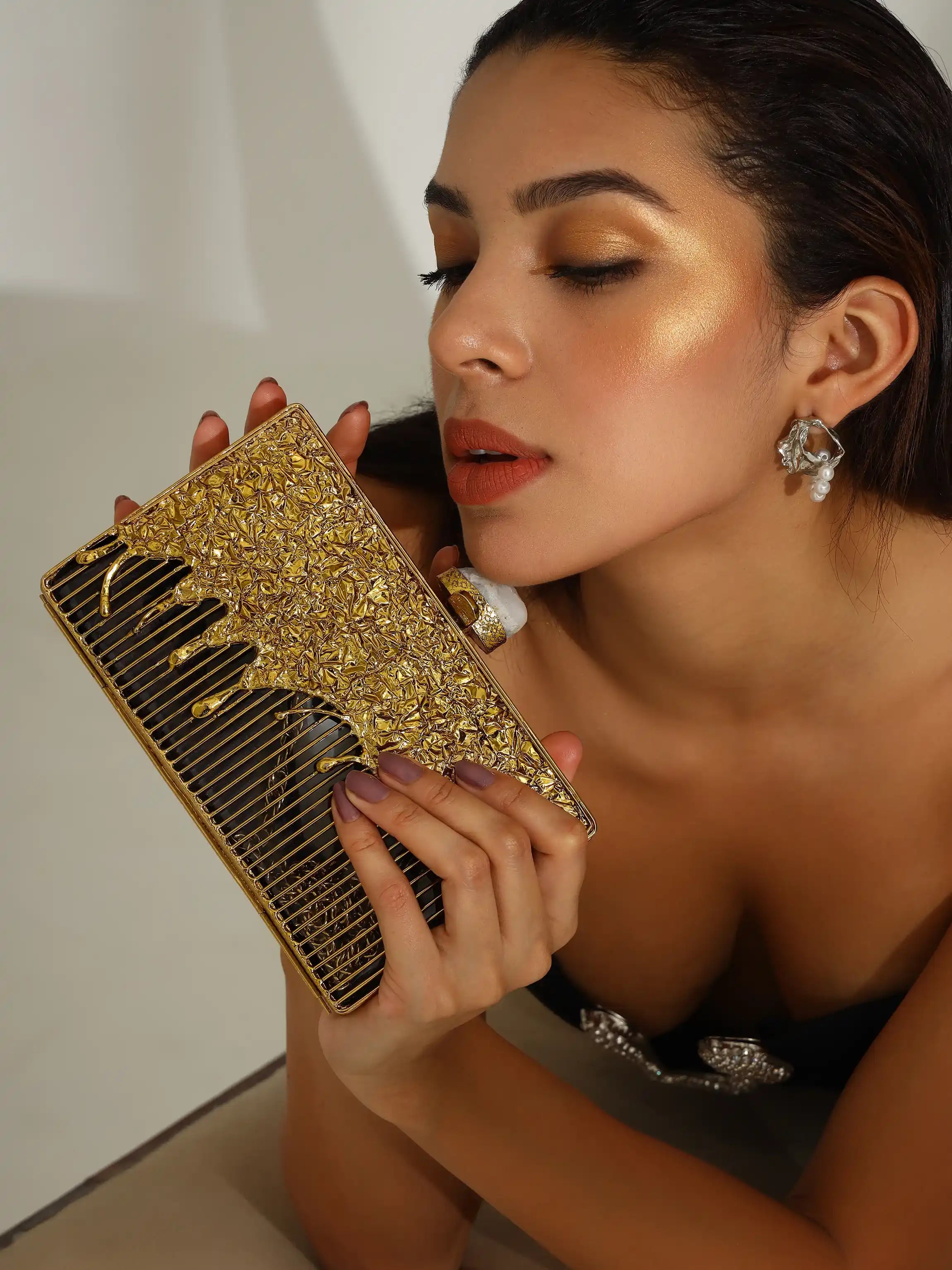 Woman holding a gold comb with a white background