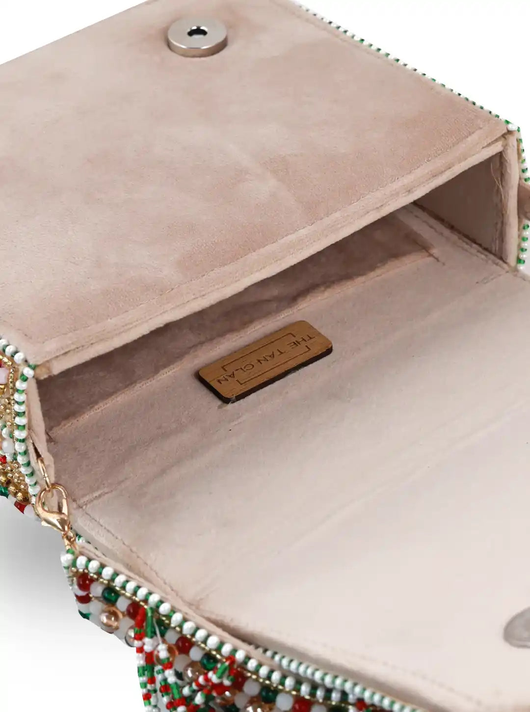 Close-up of a beige handbag with decorative beads and a visible brand label.