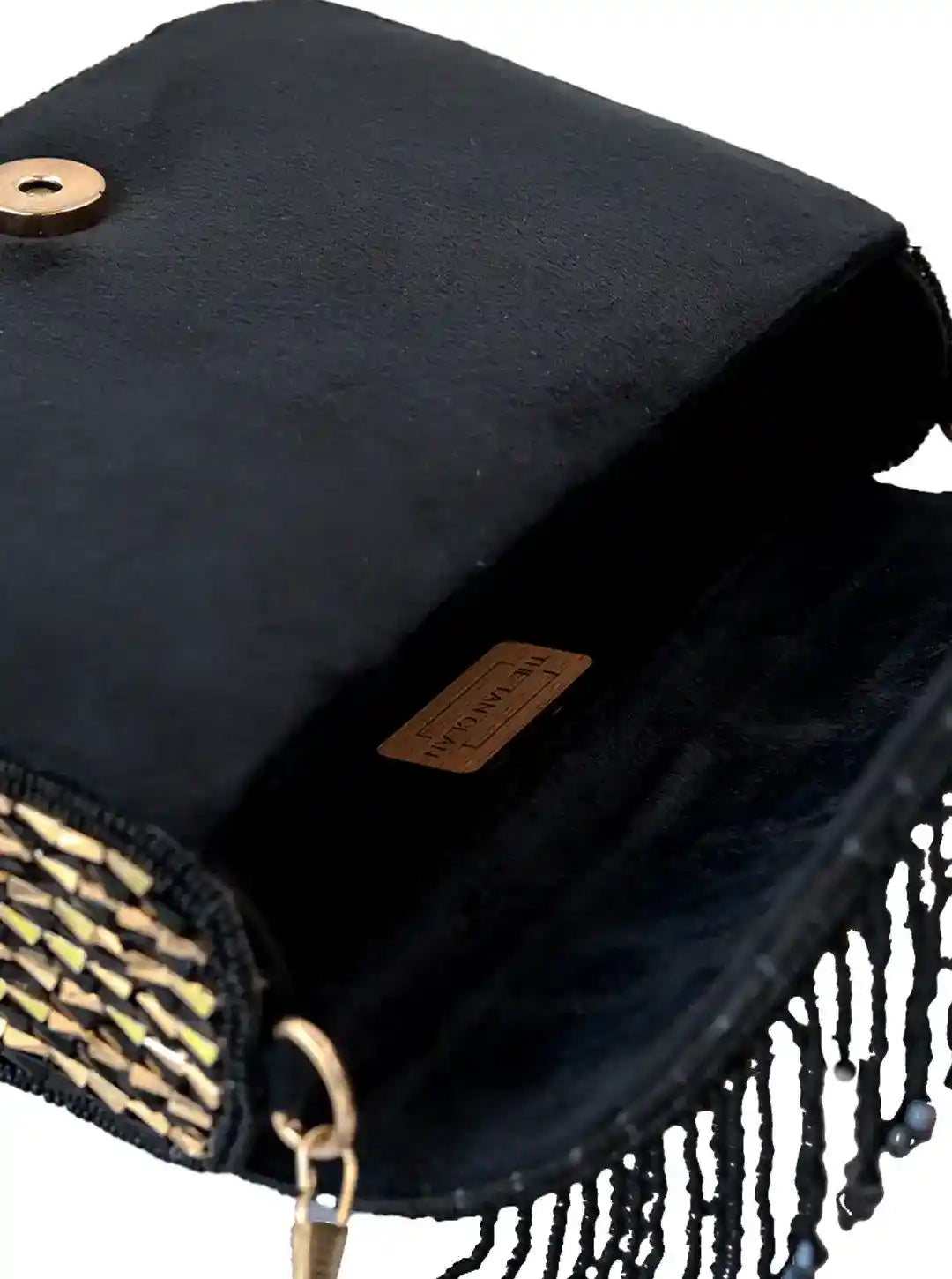 Black handbag with fringes and a gold clasp on a white background