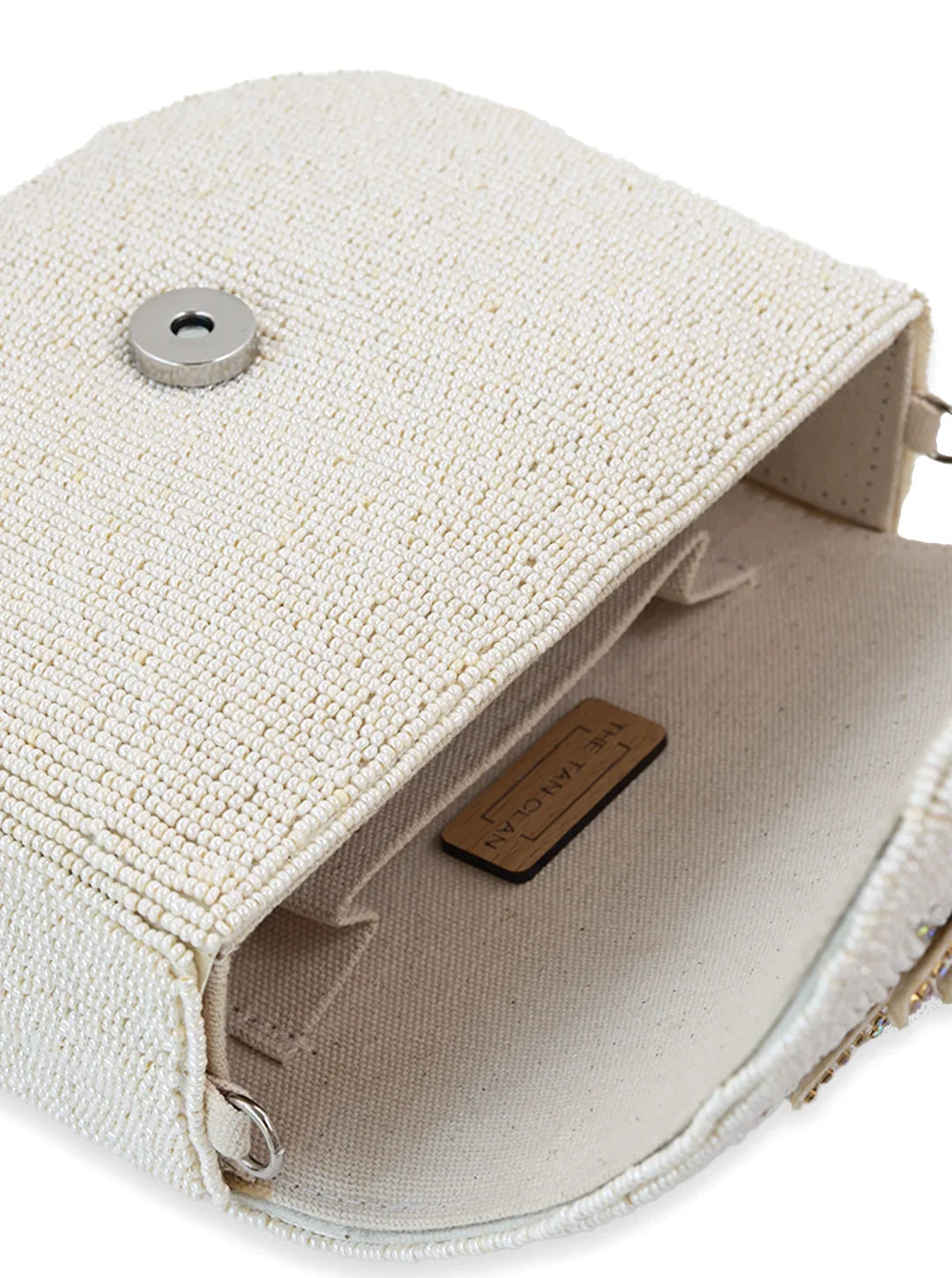 Close-up of a textured beige handbag with a visible brand tag on a white background
