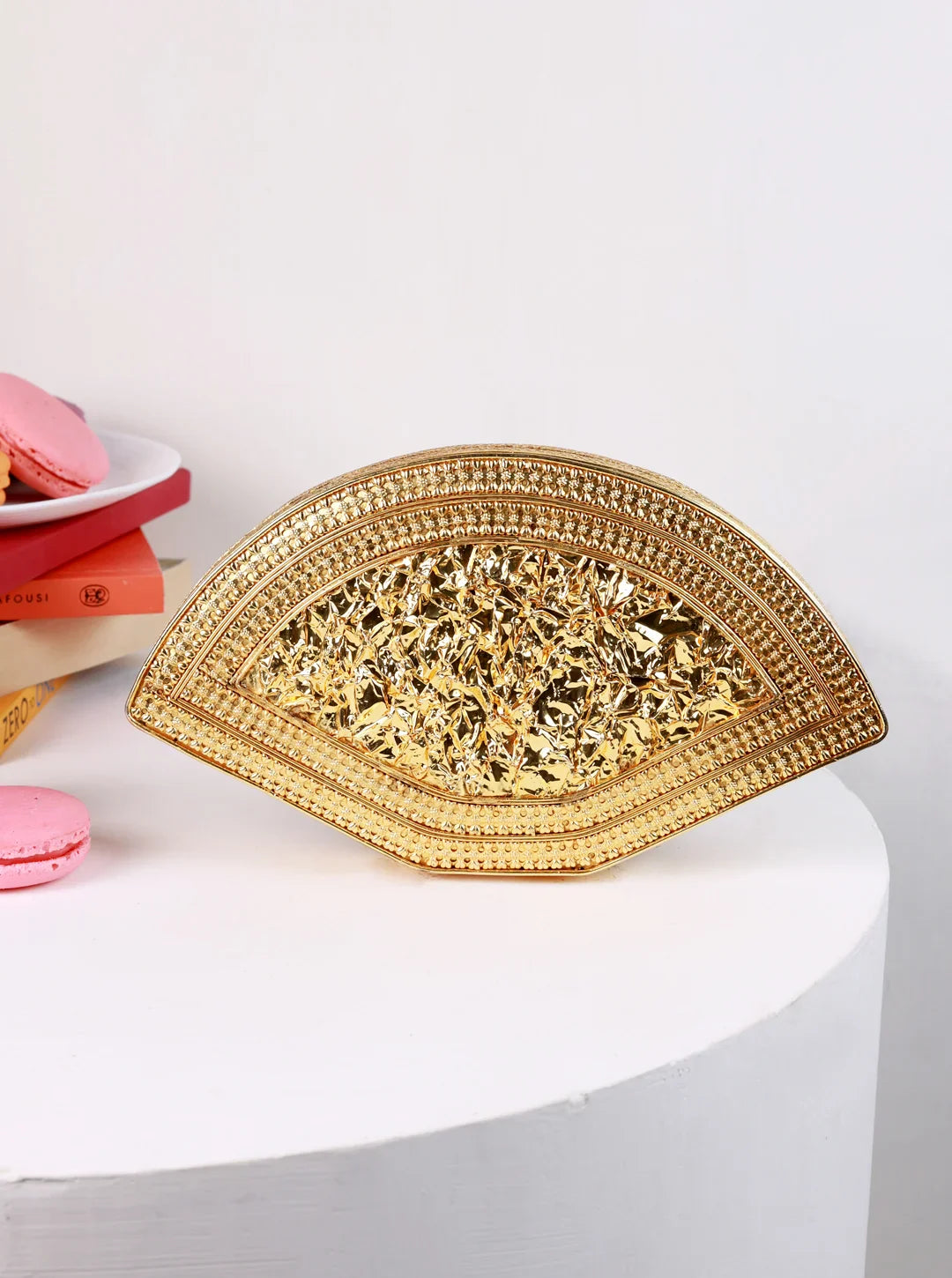 Gold decorative plate on a white surface with pink macarons in the background