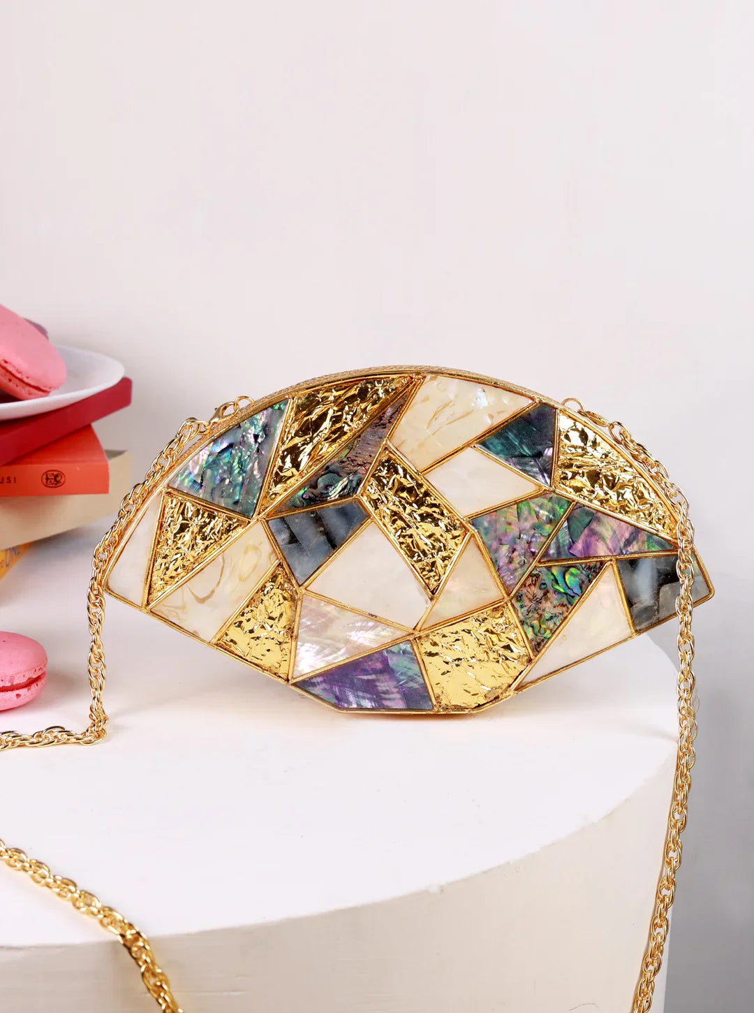 Decorative handbag with geometric design and gold chain on a white surface