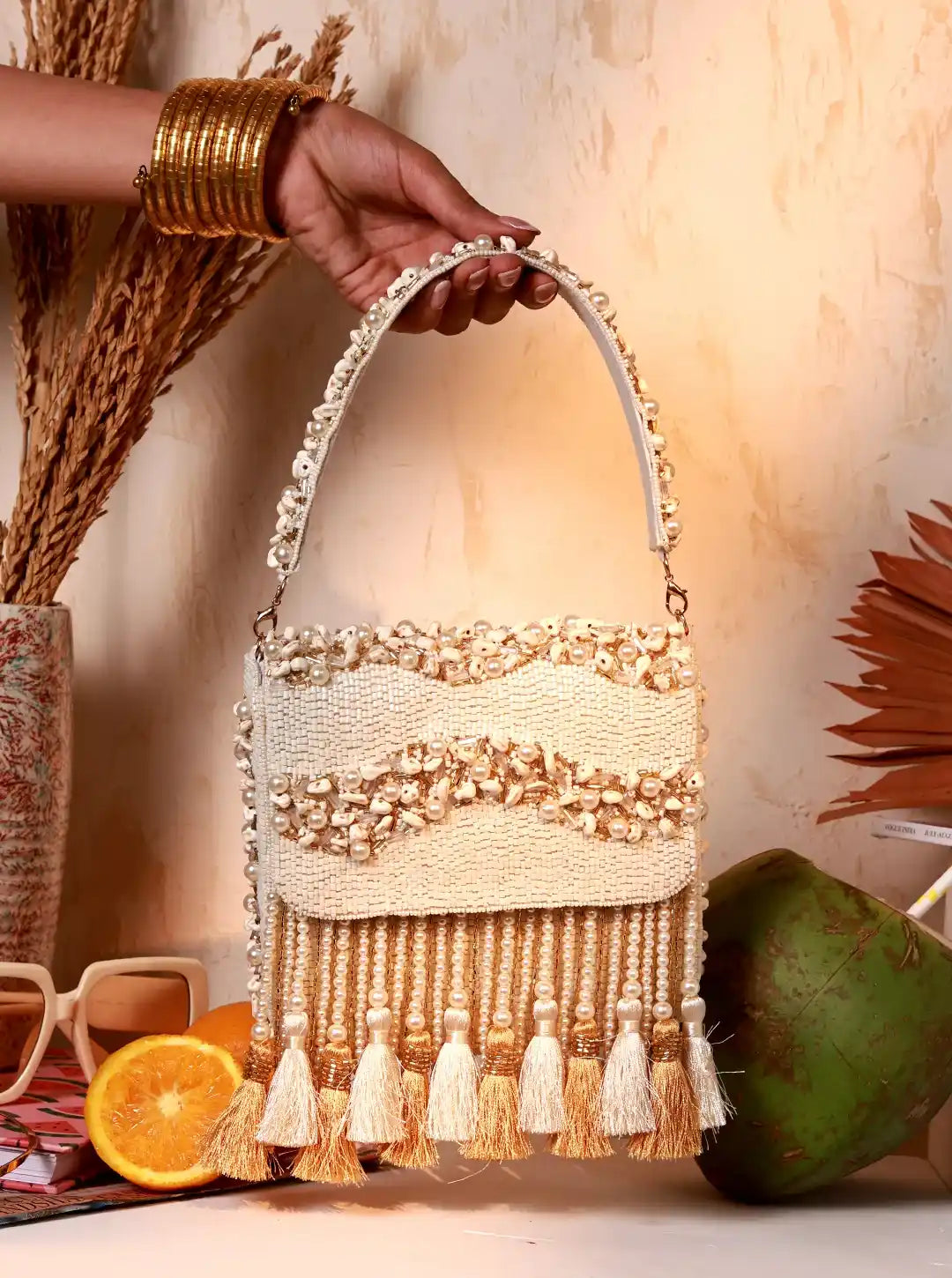 Handbag with tassels held by a hand, with a warm-toned background
