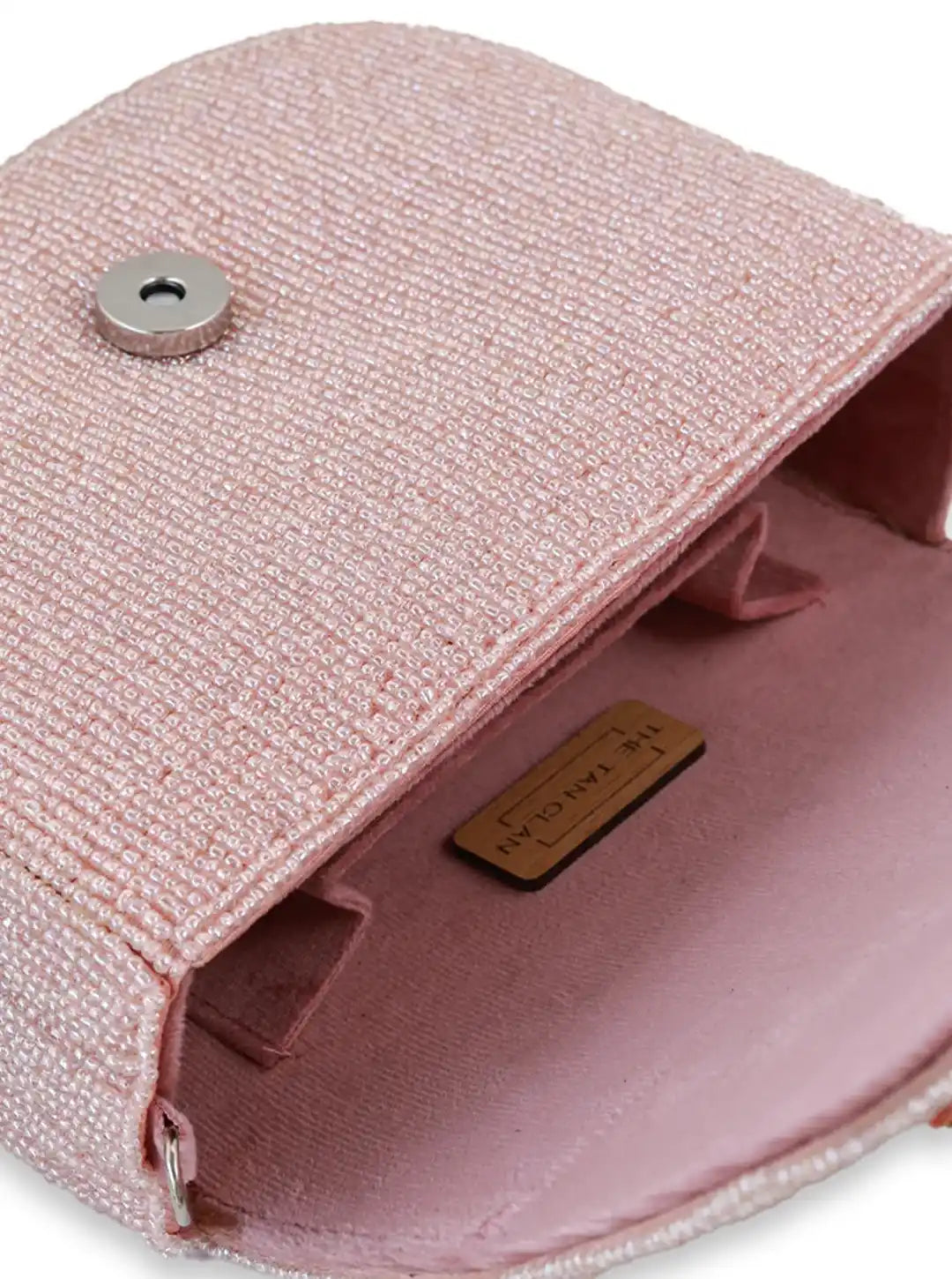 Close-up of a pink textured pouch with a metal button and brand label on a white background