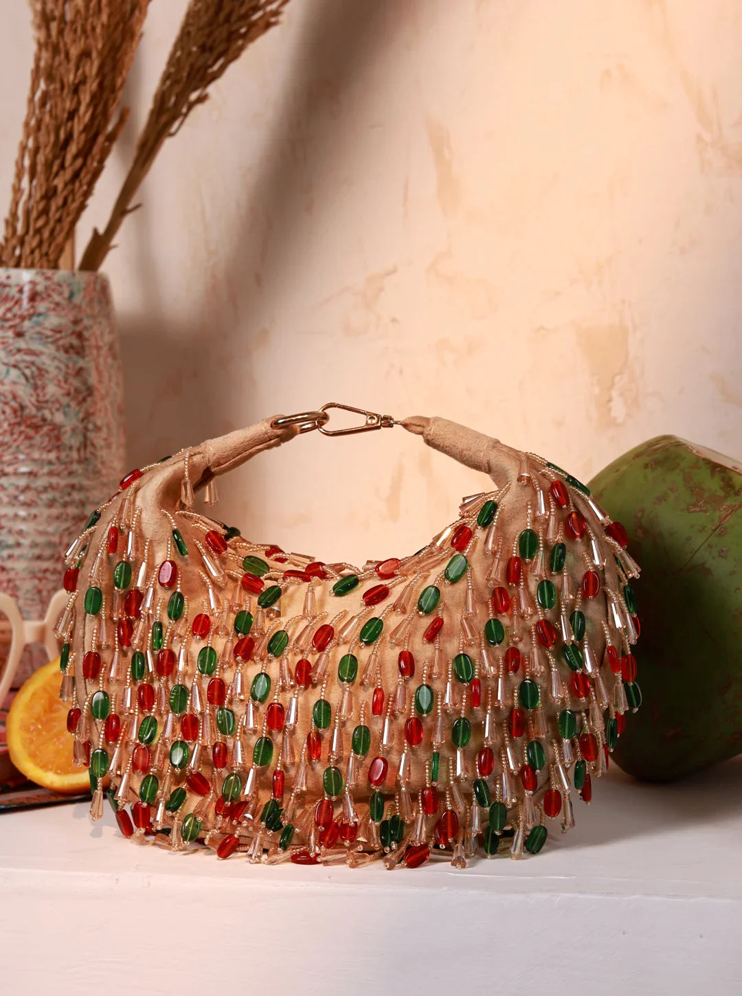 Beaded handbag with red and green accents on a neutral background
